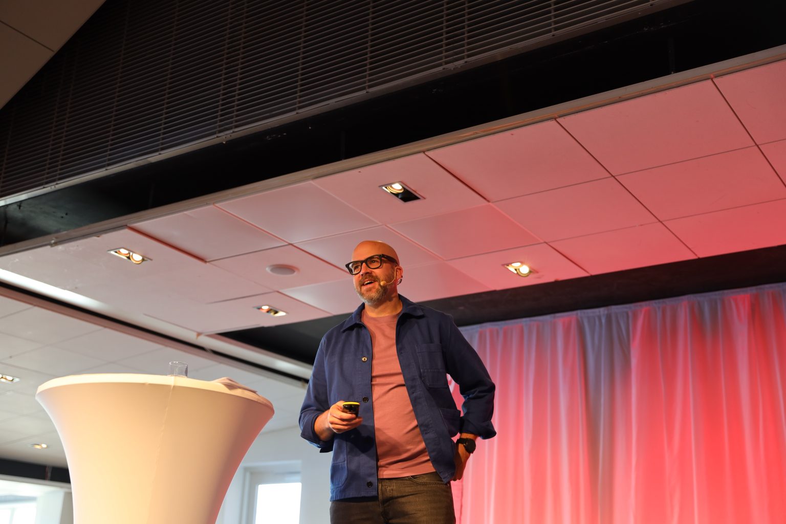 Johannes Sundlo föreläser på scen med headset och presentationsfjärrkontroll.