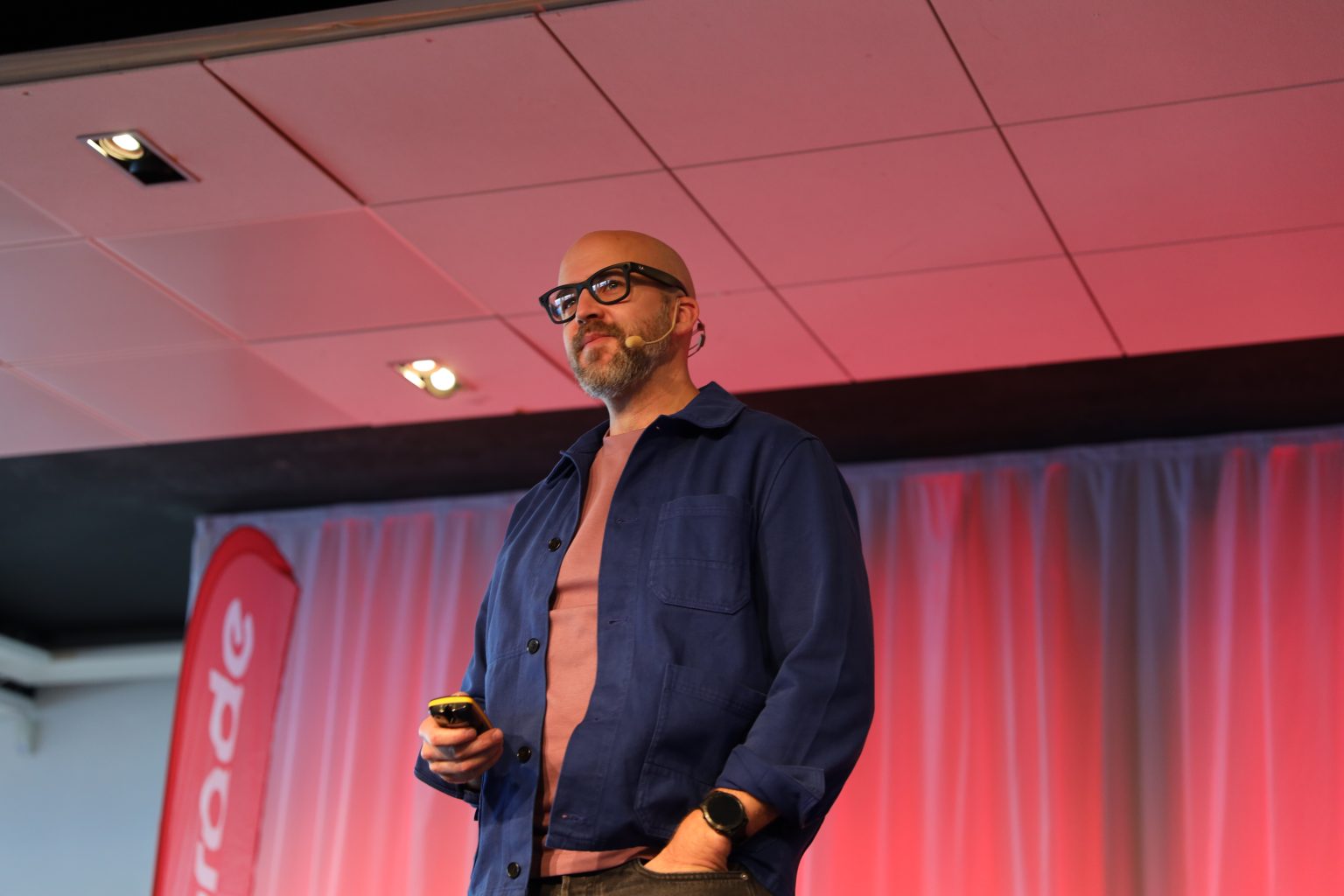 Johannes Sundlo föreläser på scen med headset och presentationsfjärrkontroll.